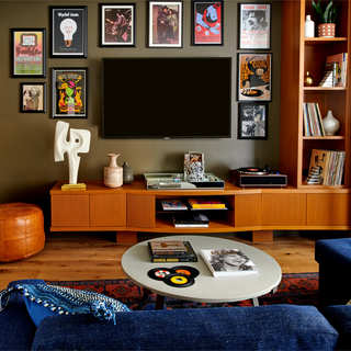 A seating area with coffee table, side table holding artwork and a record player and a wall-mounted television